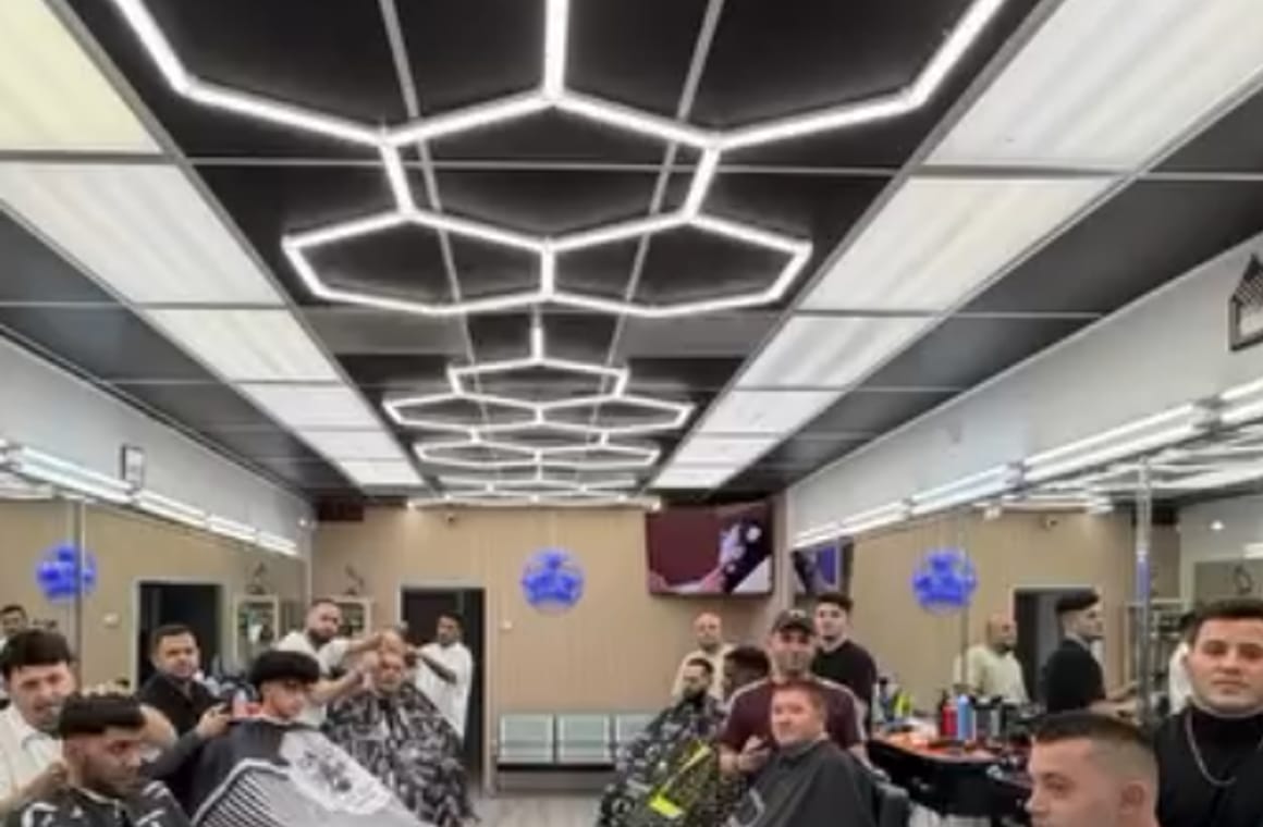 Interior de X Men Barber Shop con luces hexagonales y sillas llenas un sábado